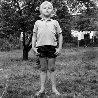 Young boy standing outdoors in casual clothes.