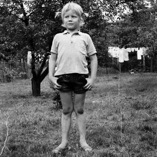 Young child standing outdoors in casual clothes.