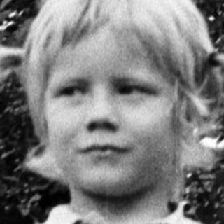 Young child standing outdoors in casual clothes.
