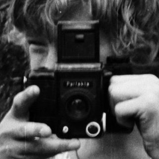 Person holding vintage camera outdoors in nature.