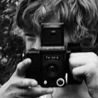 Person holding vintage camera outdoors in nature.
