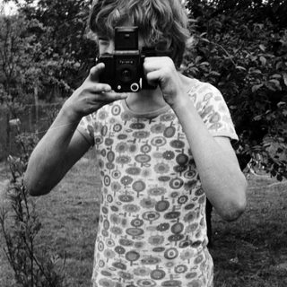 Person holding vintage camera outdoors in nature.
