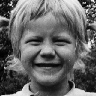 Young boy smiling outdoors in casual polo shirt.