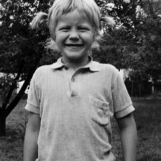 Young boy smiling outdoors in casual polo shirt.