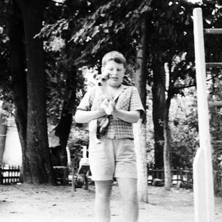 Young boy playing guitar outdoors in park.