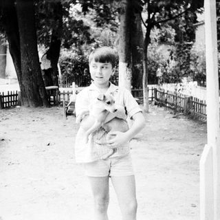 Boy holding small dog outdoors in park.