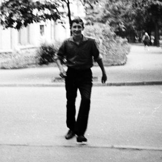Young man walking outdoors on a campus path.