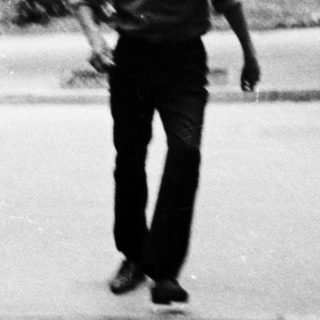 Young man walking outdoors on a campus path.