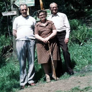Three seniors posing near hiking trail signs.