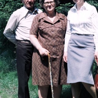 Three adults posing outdoors on a path.