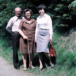 Three adults posing outdoors on a path.