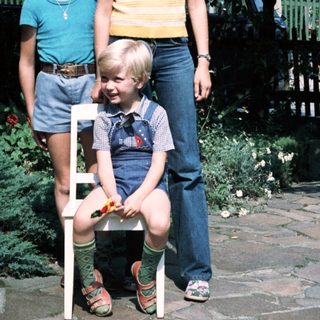 Three children posing outdoors in 1980s-style clothing.
