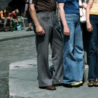 Group of eight people posing together outdoors in 1970s-style clothing.