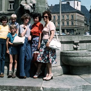 Family group photo in outdoor plaza, 1980s.