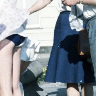 Children posing outdoors near statue, 1970s-80s style clothing.