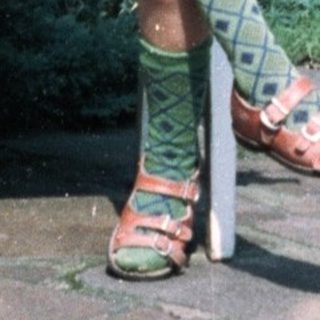 Young child sitting on chair outdoors near garden.