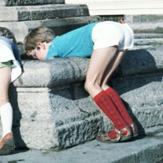 Two children playing near a fountain statue.
