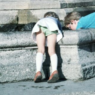 Two children playing near a fountain statue.