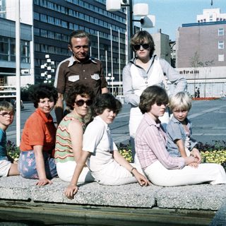 Group photo of adults and children outdoors in 1970s style clothing.