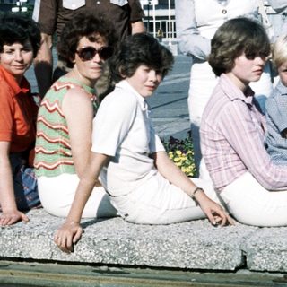 Group photo of adults and children outdoors in 1970s style clothing.