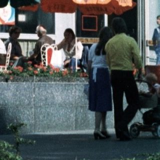 Two children posing near a decorative monument in an urban plaza.