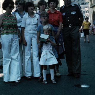 Family group posing in front of historic European town square.