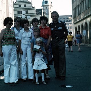 Family group posing in front of historic European town square.