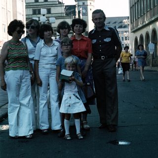 Family group posing in front of historic European town square.