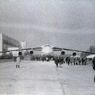 Large aircraft on snowy airfield with crowd observing.