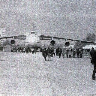 Large aircraft on snowy airfield with crowd observing.