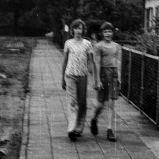 Two individuals walking on a paved path beside a construction area.