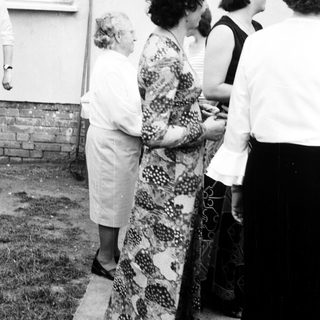 Four women standing outdoors near a fence.