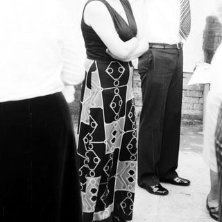 People standing outdoors, man adjusting woman's blouse.