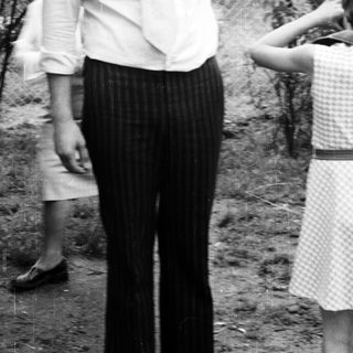 Man in 1970s-style clothing standing outdoors.
