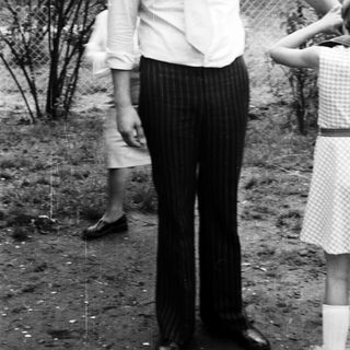 Man in 1970s-style clothing standing outdoors.