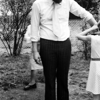 Man in 1970s-style clothing standing outdoors.