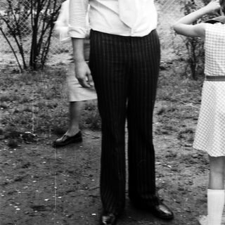 Man in 1970s-style clothing standing outdoors.