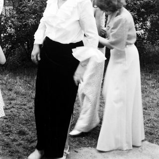 Two women outdoors, one adjusting the other's dress.