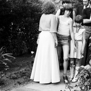 Group of people gathered outdoors in 1970s attire.