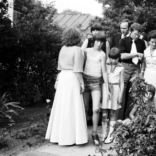 Group of people gathered outdoors in 1970s attire.