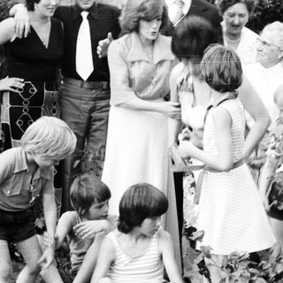 Family gathering outdoors playing with garden hose.