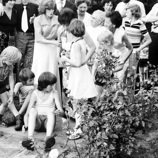 Family gathering outdoors playing with garden hose.