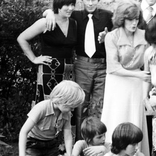 Family gathering outdoors playing with garden hose.