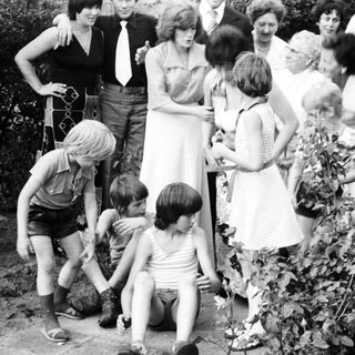 Family gathering outdoors playing with garden hose.