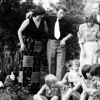 Family gathering outdoors in garden, 1970s.