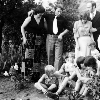 Family gathering outdoors in garden, 1970s.