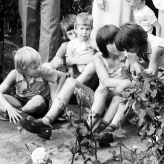 Family gathering outdoors in garden, 1970s.