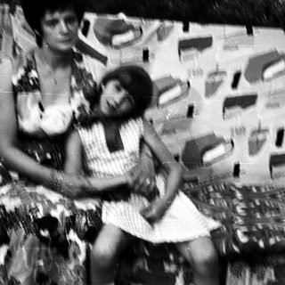Two women posing on a patterned wall.