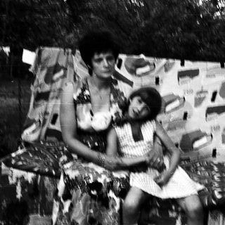 Two women posing on a patterned wall.