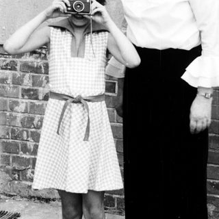 A woman teaching a young girl to use a camera.